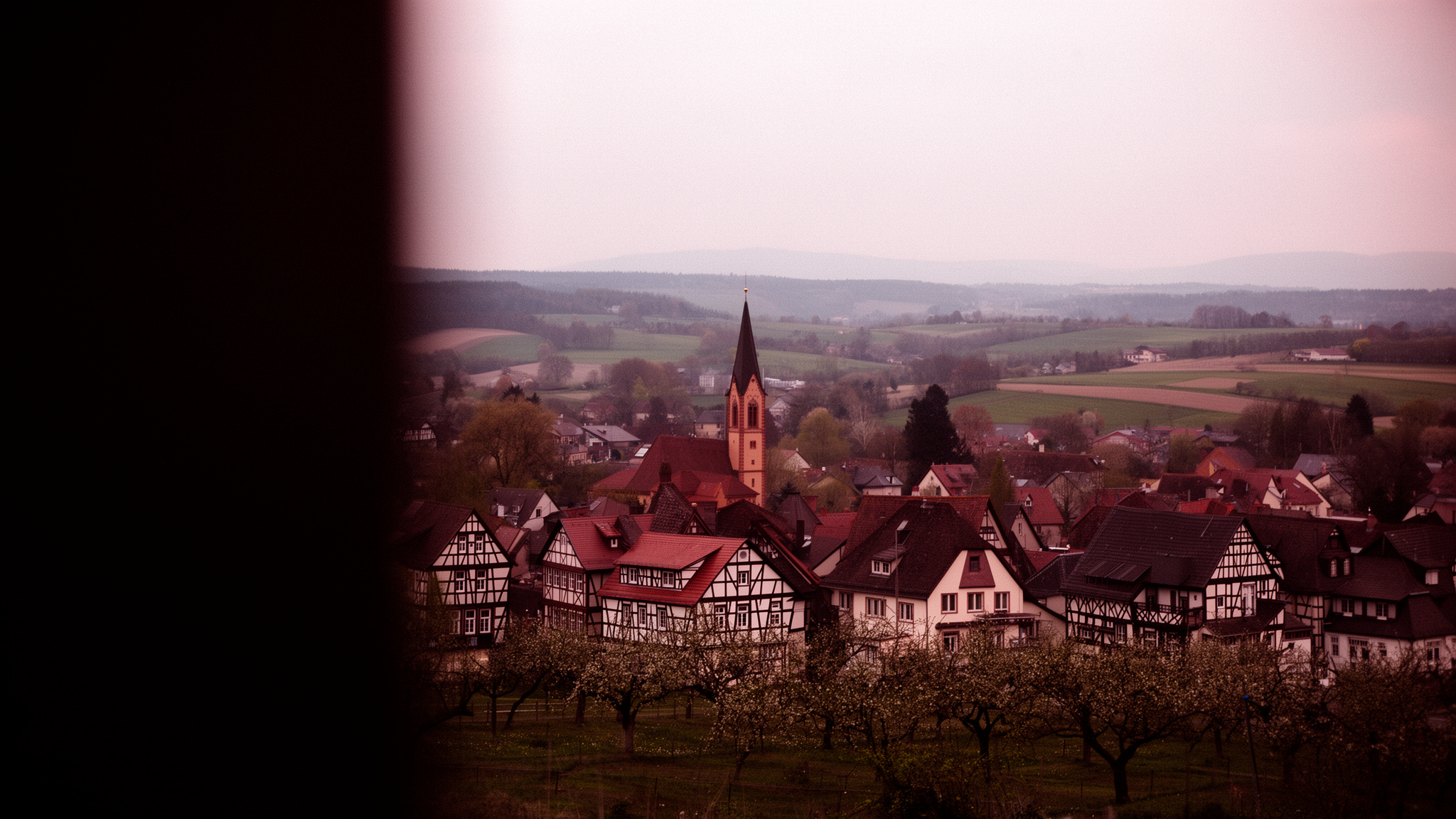 Blick vom Feldweg über die Dächer von Eichenzell hinab in das grüne Fuldatal bei warmem Abendlicht